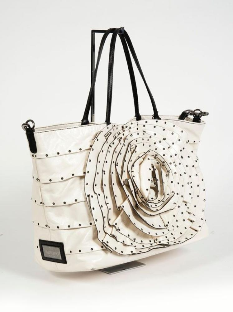 VALENTINO

Sac 40cm en cuir ivoire ajouré d’oeillets, devant à effet de corolles, double poignée en cuir noir, anse bandoulière amovible. Bon état
