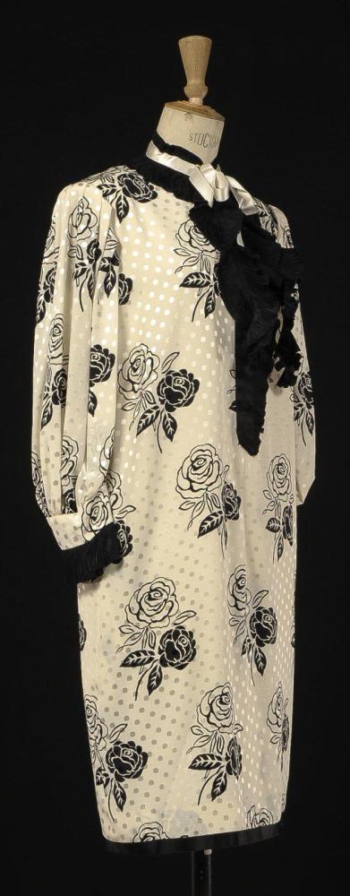 Emanuel UNGARO

Couture N°7216, Printemps - Eté 1982 Robe de forme droite en soie écrue à motif floral et pois damassés, encolure jabot et bas des manches longues en soie plissée noire, manches longues. Griffe blanche, graphisme noir.