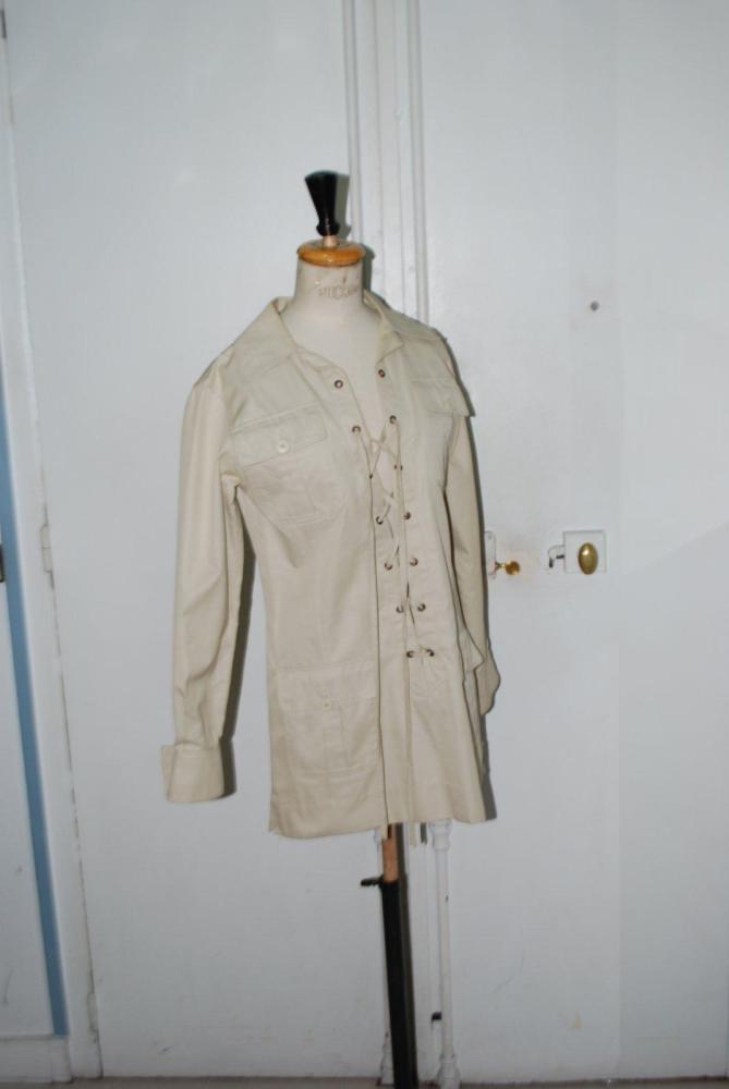 SAINT LAURENT Rive Gauche, circa 1969

Tunique saharienne en gabardine de coton beige, petit col, devant lacé, quatre poches manches longues. Griffe blanche, graphisme noir réhaussé de deux carrés couleur