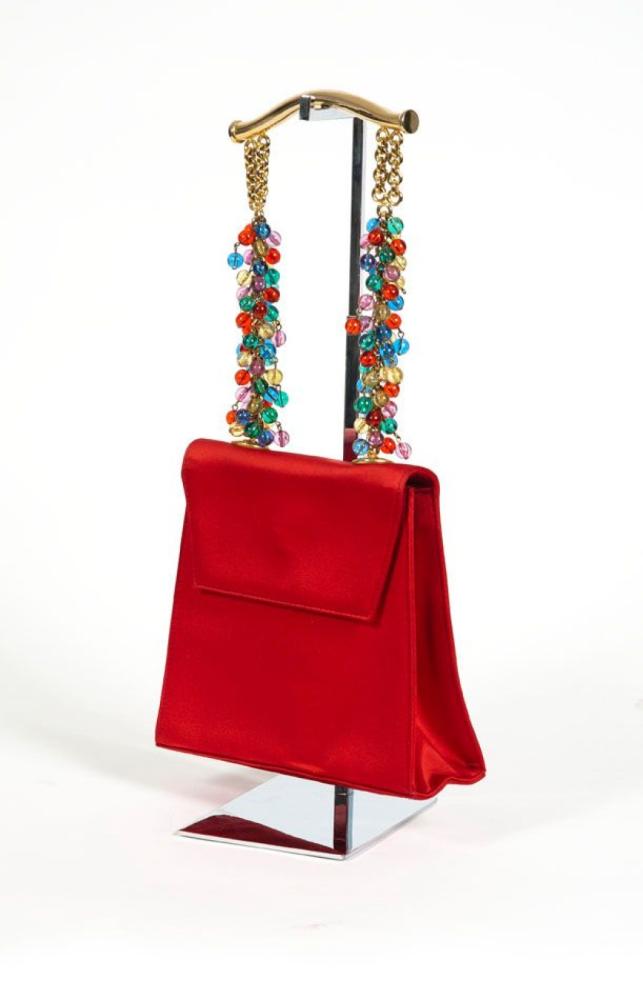 Gianni VERSACE couture

Sac du soir 21 cm en satin rouge de forme trapèze, fermeture aimantée sous rabat, poignée en métal doré d’inspiration asiatique se continuant par des perles en composite multicolor, poche intérieur, salissures