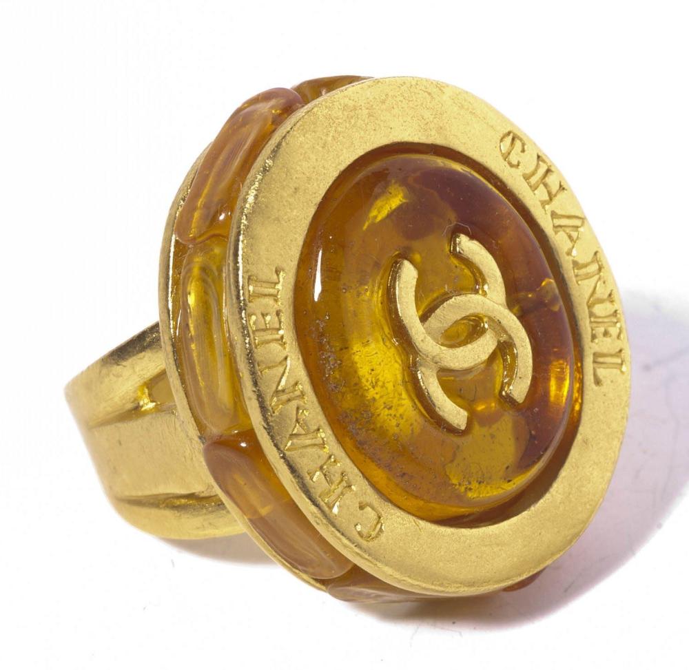 CHANEL

Bague en métal doré amati orné de résine façon ambre rehaussé du sigle et d’écritures. Signée