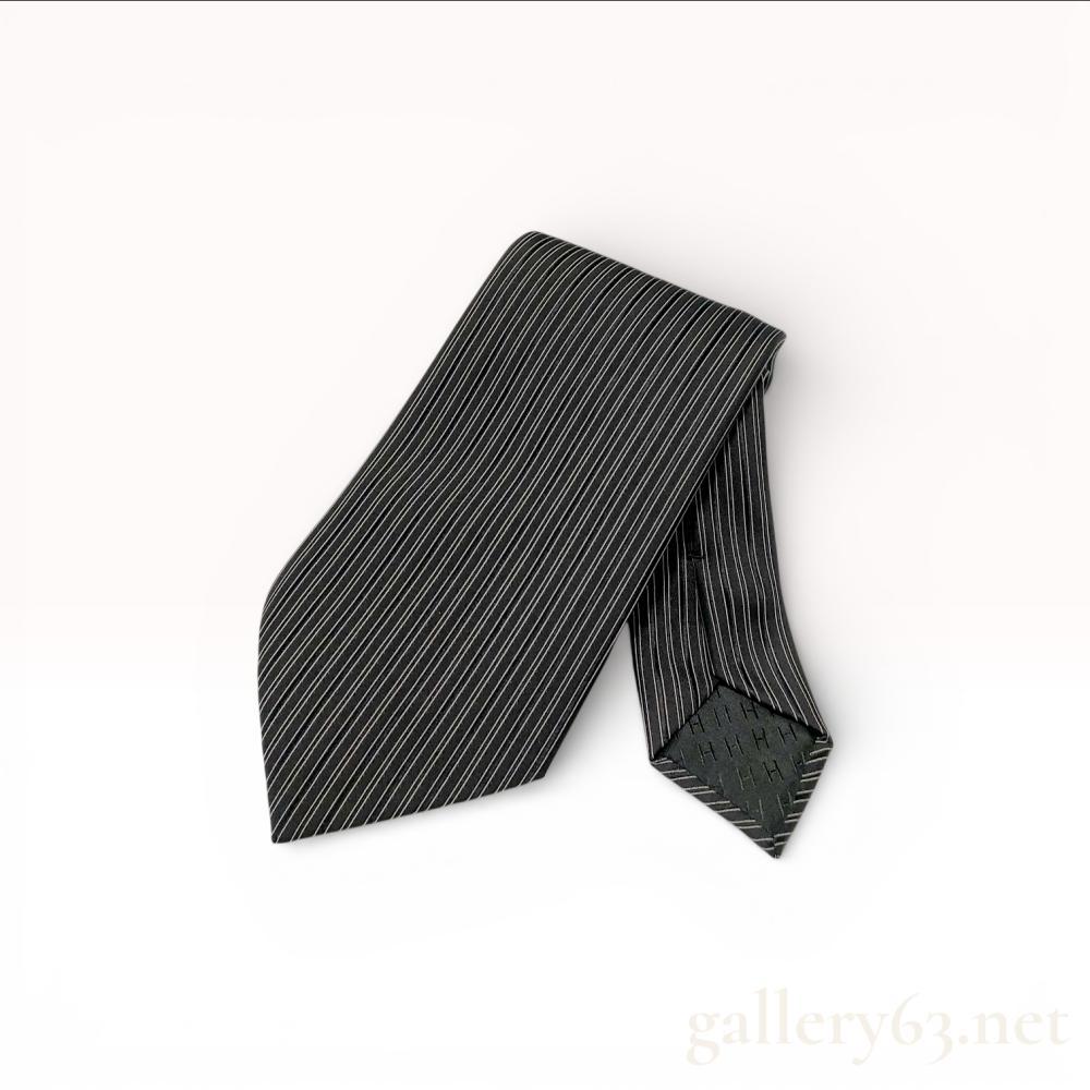 Description
Hermes silk necktie featuring a pattern of fine horizontal pinstripes in white and light grey on a black ground. The accessory is constructed from 100 percent silk and includes a tonal black silk jacquard lining with a repeating H pattern. The keeper loop is woven with the Hermes-Paris name and horse and carriage logo, while the narrow end features a printed logo and copyright mark.
Length: 57 inches
Width: 3.5 inches.