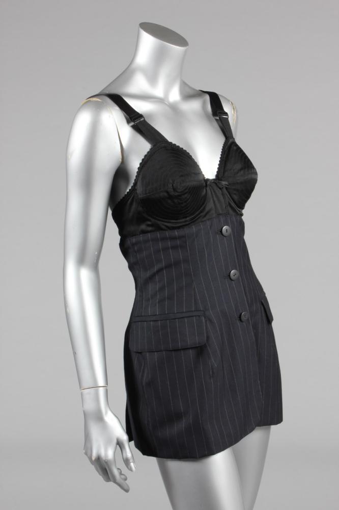 

A Jean Paul Gaultier ’corset’ bodice, circa 1987, labelled ’Femme’ and  Italian size 42, of navy-blue pin-striped suiting, button fastened and with padded black satin under-wired breasts, lined in striped satin, bust approx 86-92cm, 34-36in
