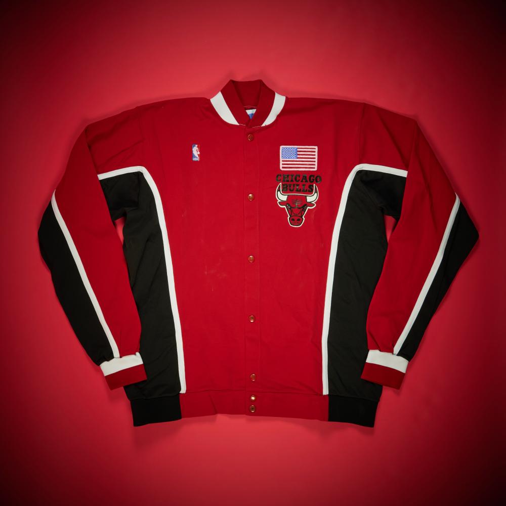Scottie Pippen Chicago Bulls Game Worn Warmup Jacket | Circa 1990-1992

CHAMPION, CHICAGO BULLS RED JACKET

Presented in this lot is a game-worn red Chicago Bulls warmup jacket used during the 1990-1991 or 1991-1992 season. The jacket was worn during a contest against the Miami Heat. While the available photographs are not dated to a specific game, multiple images confirm the matchup, including one identified as AP #965442387455 that captures Scottie Pippen posing alongside the Miami Heat mascot. Warmups from this era are among the most visually iconic elements of Bulls game presentation.

The jacket features the classic red Chicago Bulls design, highlighted by the team’s bull logo accented with an American flag on the right chest.

From 1990 through 1992, the Chicago Bulls evolved from a talented contender into a championship dynasty, and at the heart of that transformation was Scottie Pippen. While Michael Jordan remained the league’s most electrifying scorer, it was Pippen’s emergence as an elite two-way force—capable of guarding every position, initiating offense, and elevating the team’s defensive identity—that allowed the Bulls to finally break through at the highest level.

During the 1990–91 season, Pippen’s development into a true superstar gave head coach Phil Jackson the versatility required to fully implement the triangle offense. Pippen functioned as a point-forward within the system, facilitating ball movement, pushing the pace in transition, and anchoring Chicago’s aggressive perimeter defense. His length and defensive instincts were crucial in neutralizing opposing stars throughout the playoffs, particularly during the Eastern Conference Finals sweep of the Detroit Pistons that symbolically ended Detroit’s dominance and ushered in a new era in the NBA. Chicago went on to defeat the Los Angeles Lakers in five games to capture the franchise’s first championship.

By 1991–92, Pippen had firmly established himself as one of the most complete players in basketball. He earned First Team All-Defense honors and his first All-NBA selection while helping lead the Bulls to a franchise-record 67 wins. Beyond the box score, his ability to handle the ball, initiate offense, and defend elite wings and guards allowed the Bulls to play a uniquely fluid and switchable style. That versatility proved decisive in the Finals against the Portland Trail Blazers, where Chicago secured its second consecutive championship.

This jacket comes directly from the Collection of Scottie Pippen.

This jacket has been photo matched by PSA.