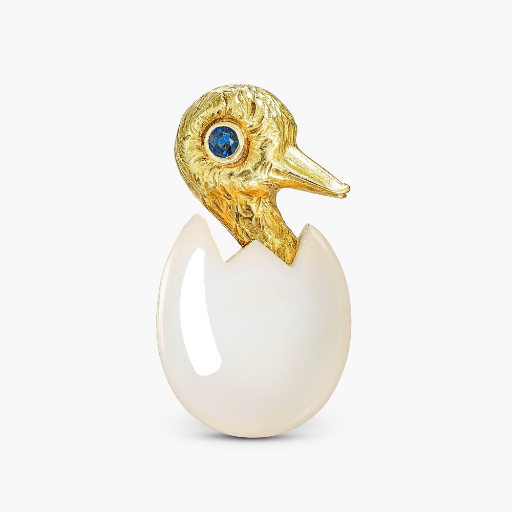 Cartier

Designed as a chick emerging from a cracked carved chalcedony egg, accented by sapphire eye