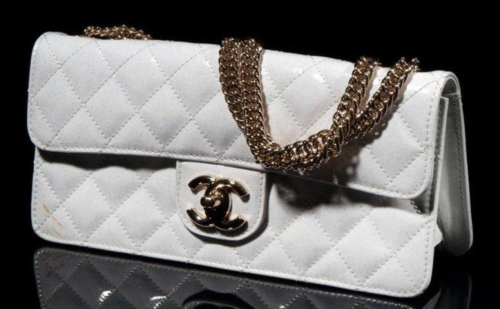 CHANEL

Sac en cuir vernis matelassé blanc chiné or, femoir siglé sur rabat, double anse chaines en métal doré (tache)