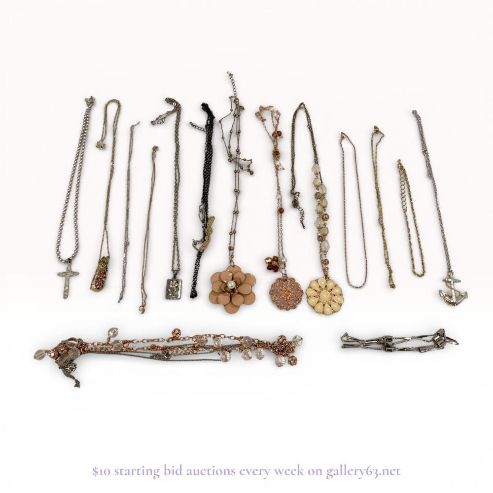 Description
A collection of contemporary fashion costume jewelry, late 20th to early 21st century. The group includes various necklaces and chain-link extenders featuring floral, nautical, and whimsical motifs such as a silver-tone anchor, an owl with pink rhinestones, and enamel flower pendants. Items are constructed from gold-tone, silver-tone, rose gold-tone, and antiqued brass-tone base metals accented with faux pearls, faceted glass beads, and clear rhinestones. Markings are present on several lobster claw clasps and metal tags but are not clearly legible.