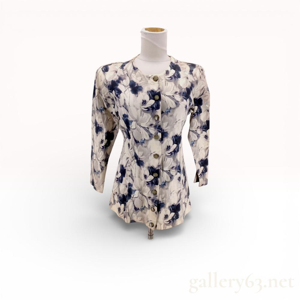 Description
Christian Dior Sports tunic-length button-front jacket, circa late 1980s to 1990s. The garment is constructed from a fine-gauge jersey knit featuring a watercolor-style floral print in navy and grey tones on a cream ground. Design elements include vertical princess seams for a tailored fit, a rounded neckline, and nine marbled domed plastic buttons. Interior features a woven Christian Dior Sports label and a size M tag.
