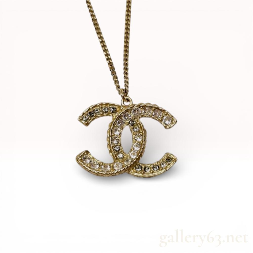 Description
Chanel interlocking CC logo pendant necklace from the Spring 2015 collection. The double-sided gold-tone metal pendant features a pave-set crystal obverse and a cream enamel reverse within a rope-textured border, suspended from a flat curb link chain. The lobster claw clasp is marked CHANEL B15 C and MADE IN ITALY, with an extender terminating in two small CC charms.
Length: 23 inches
Pendant Width: 1.18 inches.