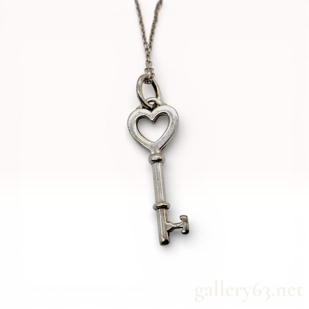 Description
Tiffany & Co. sterling silver heart key pendant necklace from the Tiffany Keys collection. The pendant features an open heart-shaped bow with a traditional key shaft and bit, suspended from a delicate cable link chain with a spring ring clasp. The pendant stem is stamped with the mark ©T&CO.925, and the chain tags are marked TIFFANY & CO. and SPAIN.
Chain length: 18 inches
Pendant length: 1.25 inches.