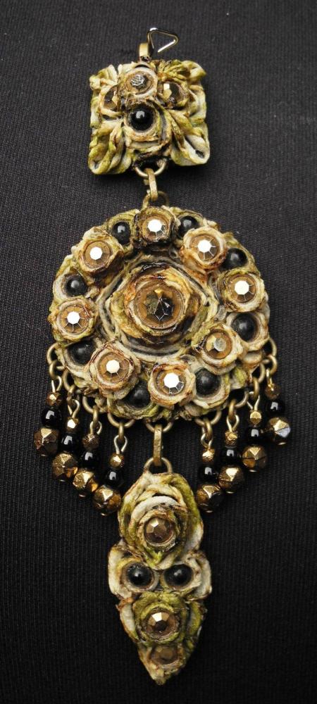 HENRY - circa 1960

Pendentif articulé en résine gravée rehaussée de strass et cabochons en pâte de verre marrons Le médaillon central se finit par des pendeloques Signé au revers du médaillon central et marqué "EXCLUSIF"