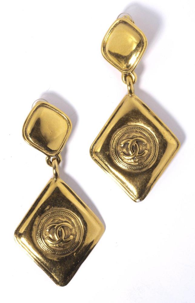 CHANEL

Paire de pendants d’oreilles en métal doré rehaussé du sigle. Signée