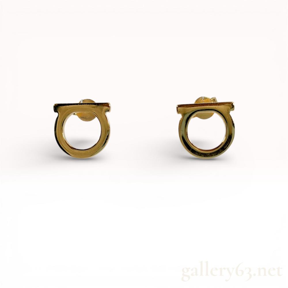 Description
Salvatore Ferragamo Gancini stud earrings in gold-tone metal. Each earring features the signature horseshoe-shaped logo with a horizontal bar and is secured with friction butterfly backs. The reverse of each piece is incised with the Ferragamo script signature and MADE IN ITALY. The lot includes the original red presentation box and a red velvet-texture drawstring pouch.
Width: 1 cm.