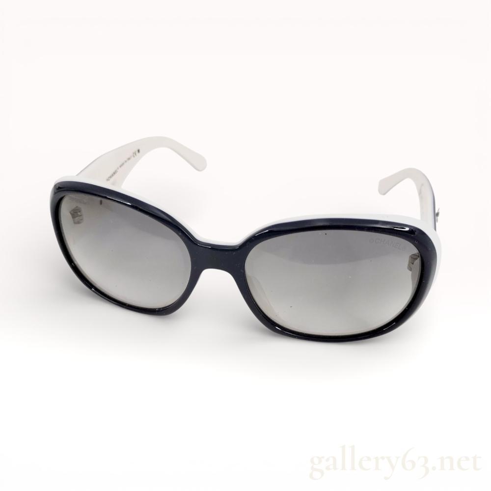 Description
Authentic Chanel Camellia model 5113 sunglasses featuring a navy blue oval frame fitted with grey-tinted lenses. Arms finished in contrasting white, accented with Camellia motif detailing at the temples. Classic Chanel eyewear design combining sculptural form with subtle signature elements.