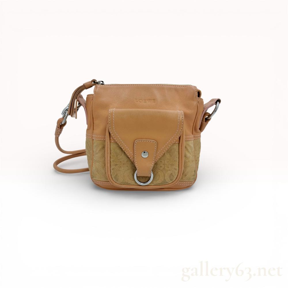 Description
Loewe shoulder bag having a compact rectangular form with zip-top closure and front flap pocket. Featuring tan suede panels embossed with the Loewe anagram pattern, framed by smooth leather trim. Set with silver-tone hardware including a front ring accent and rivet details. Having an adjustable leather shoulder strap and tonal stitching throughout. Interior lined in light fabric with a single compartment and slip pocket.