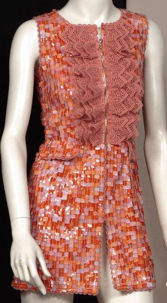 CHANEL

Mini-robe en soie saumon recouverte de pailletes en rhodoïde de formes carrées multicolores, encolure bateau, effet de jabot sur le buste par une guipure en coordonné à la doublure, sans manche, avec rappel de la guipure ainsi que l’ourlet, effet de deux poches par des rabats