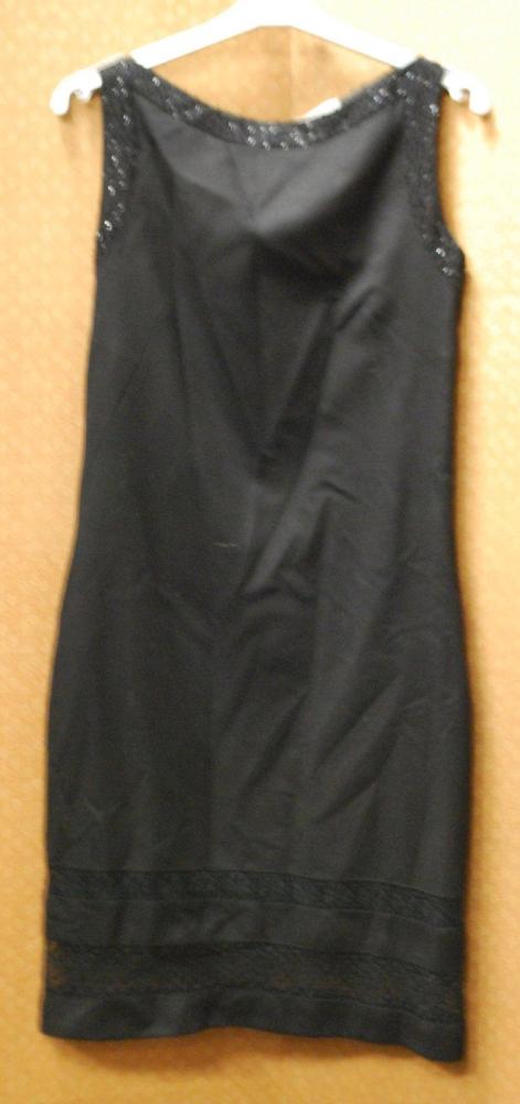 VALENTINO Miss V

Robe droite en lainage noire, encolure bateau rehaussée de perles tubulaires noire, sans manches, bas de la jupe souligné de deux bandes de guipures