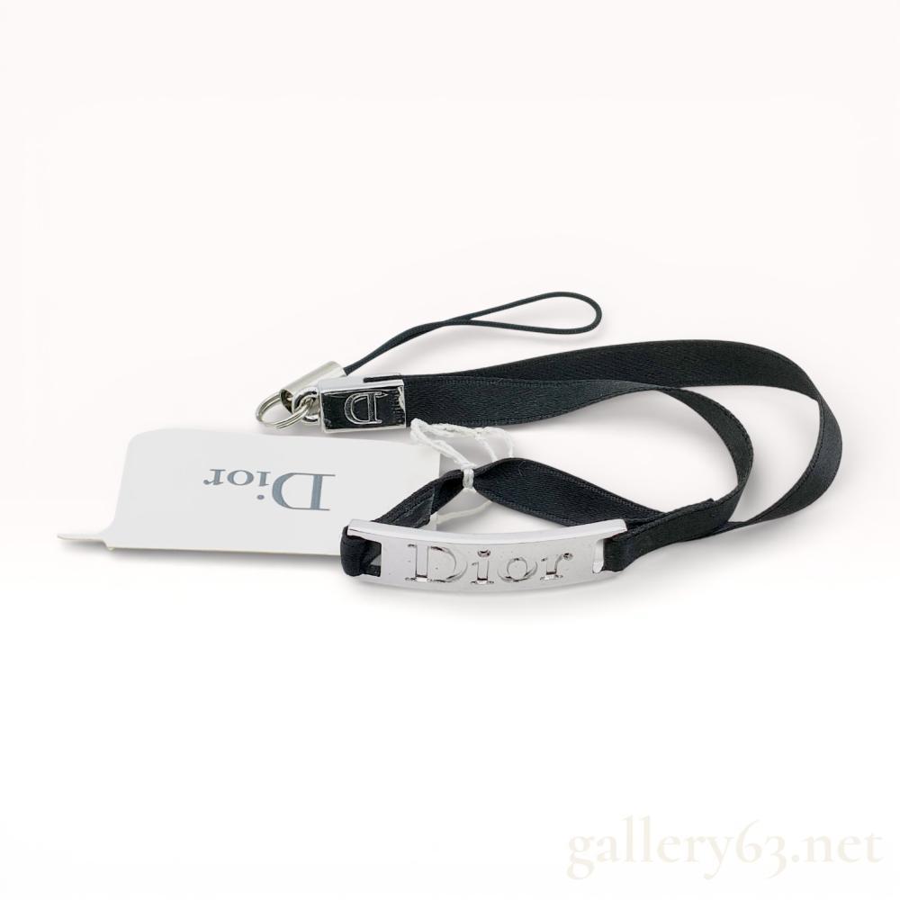Description
Christian Dior Beauty collection of four promotional jewelry items and accessories, 21st century. The set includes two adjustable cord bracelets with star and bow charms, a black satin ribbon with an embossed metal bar, and a peach logo-printed ribbon with initial charms. All pieces are constructed with silver-tone base metal and textile ribbons or cords, housed in an original silver-colored branded presentation box. Marks include embossed Dior and Dior Beauty logos on the metal charms and tags.
Black ribbon accessory: 16 cm length
Pink cord bracelet: 11 cm diameter.