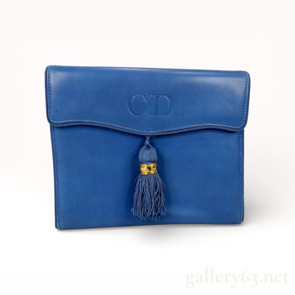 Description
Vintage Christian Dior shoulder bag having a structured rectangular silhouette in blue leather. Front flap featuring an embossed CD monogram and a centered leather tassel accent finished with gold-tone hardware detail. Interior opening to a compact lined compartment suitable for small essentials. Design presenting clean stitched edges and a minimalist profile characteristic of period Dior accessories. Authentic Christian Dior bag.