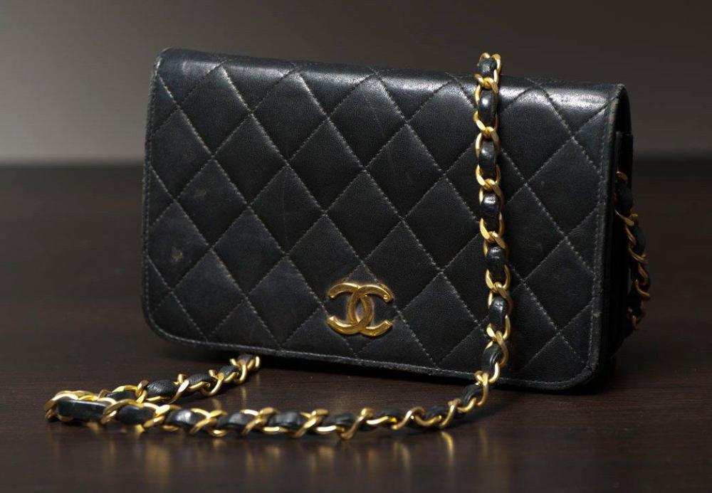 CHANEL

Petit sac en cuir agneau matelassé noir, fermoir siglé doré sur rabat, anse chaîne en métal doré entrelacé de cuir (petites usures). Long: 19 cm