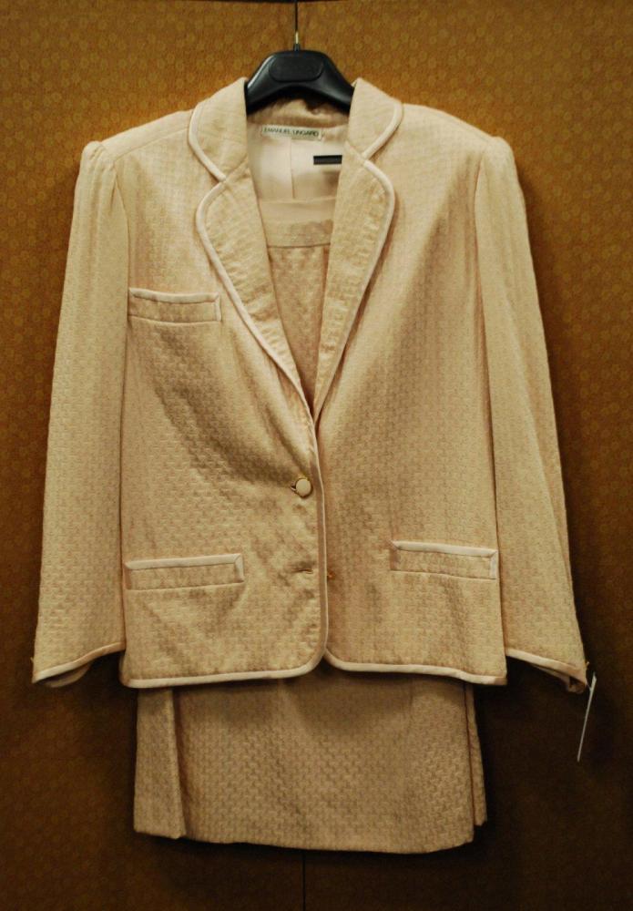 Emanuel UNGARO, patron papier, circa 1980

Tailleur en soie à effet damassé rose pâle, entièrement gansé de soie unie à la couleur, veste à col tailleur arrondi, une poche poitrine et deux poches passepoilée, manches longues, jupe évasée. Griffe blanche, graphisme noir (manque un bouton)