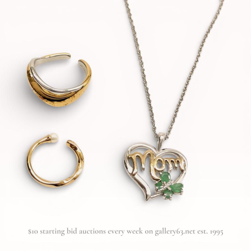 Description
This lot consists of a minimalist bypass-style ring by Japanese brand ete and a heart-shaped pendant necklace. The adjustable ring is crafted from 925 sterling silver with a two-tone gold-plated finish and overlapping wavy bands. The pendant is constructed of 925 sterling silver with 14 karat gold script reading Mom, accented by four prong-set green gemstones and a single clear stone. Marks include 925 ete on the ring interior and 925 14K A/C Â© on the pendant reverse.