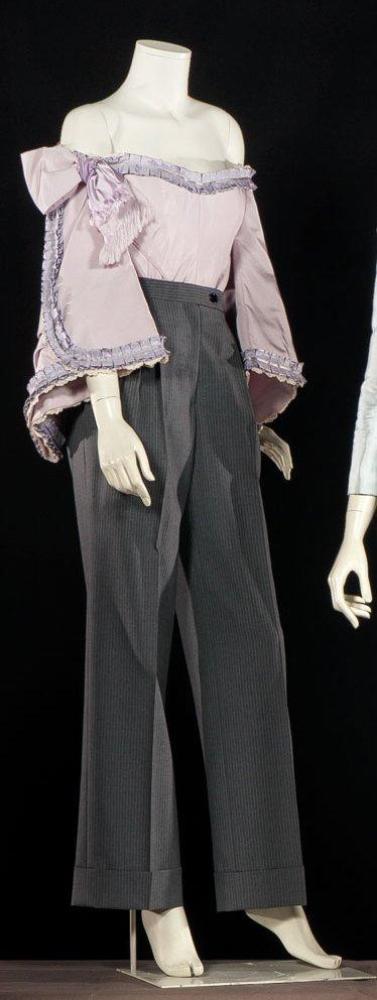 GIVENCHY par John Galliano

Haute couture, circa 1996 Atelier catherine, atelier kemal, Joy passage N°21 Ensemble composé d’un haut en reps lilas d’inspiration napoléon III, encolure bateau sur manches longues à engageantes rehaussées de rubans à plis plats mauve soulignés de guipures blanches, manches droite rehaussée d’un noeud, buste à empiècement; se porte avec un pantalon droit large en lainage gris à fines rayures tennis. Sans griffe, bolduc d’ateliers (modèle de défilé, auréoles, petits trous)