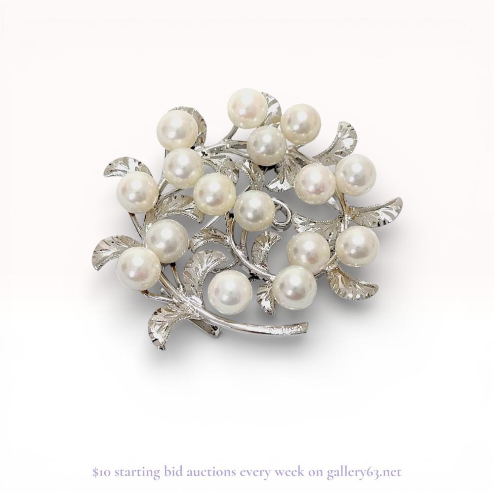 Description
Mid-century Japanese cultured pearl and silver foliate wreath brooch, featuring an integrated bail for use as a pendant. The circular design is composed of textured silver leaves set with eighteen round white cultured pearls displaying high luster and pinkish overtones. The reverse is incised with the mark SILVER and includes a straight pin with a revolving safety C-clasp.
Approximately 4.5 cm (1.77 inches) in diameter.