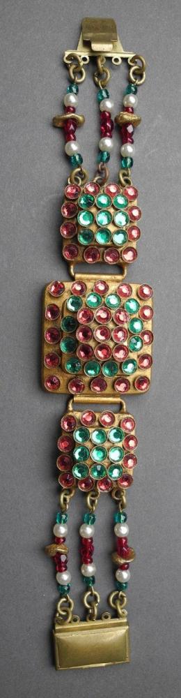 HENRY - circa 1960

Bracelet articulé composé d’éléments carrés en métal doré rehaussés de strass verts et roses Signé