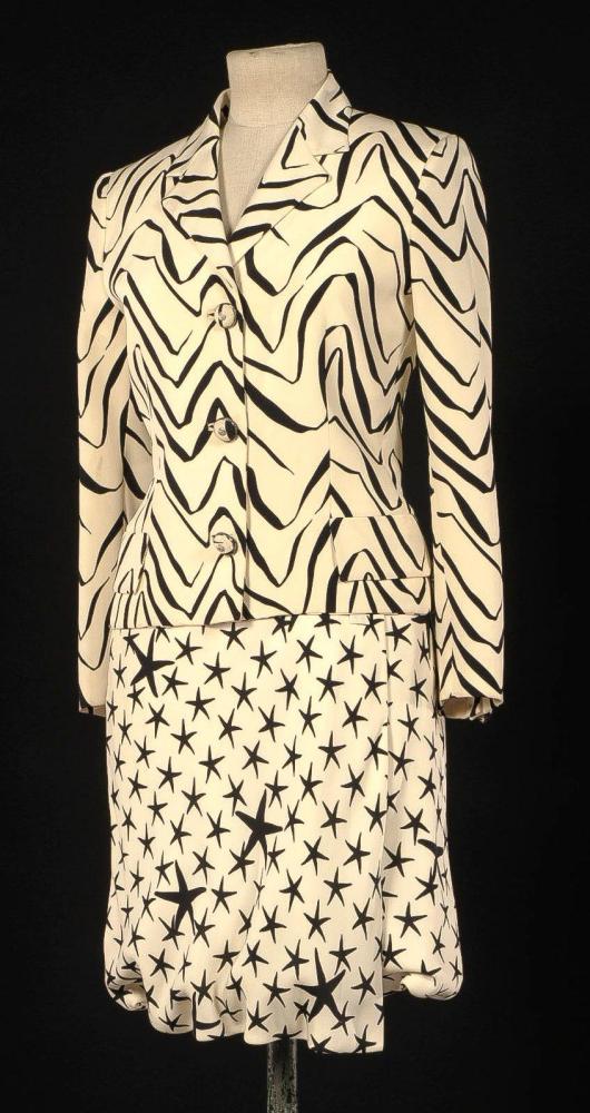 Atelier VERSACE, circa 1980

Tailleur en soie ivoire, noire, veste à impression abtstraite, col tailleur, simple boutonnage, deux rabats de fausses poches, manches longues, jupe coordonnée à impression d’étoiles. Griffe blanche, graphisme noir