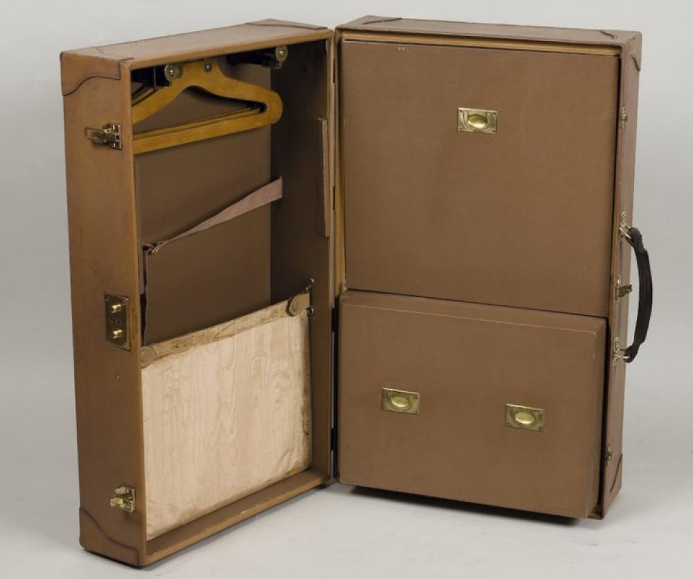 HERMES Paris

24 faubourg Saint Honoré *Wardrobe en cuir grainé beige coins renforcés, fermetures en laiton doré, poignées cuir; intérieur à deux châssis compartimentés recouverts de moire ivoire et l’autre côté faisant penderie. 49,5x28x82 cm (tâches)