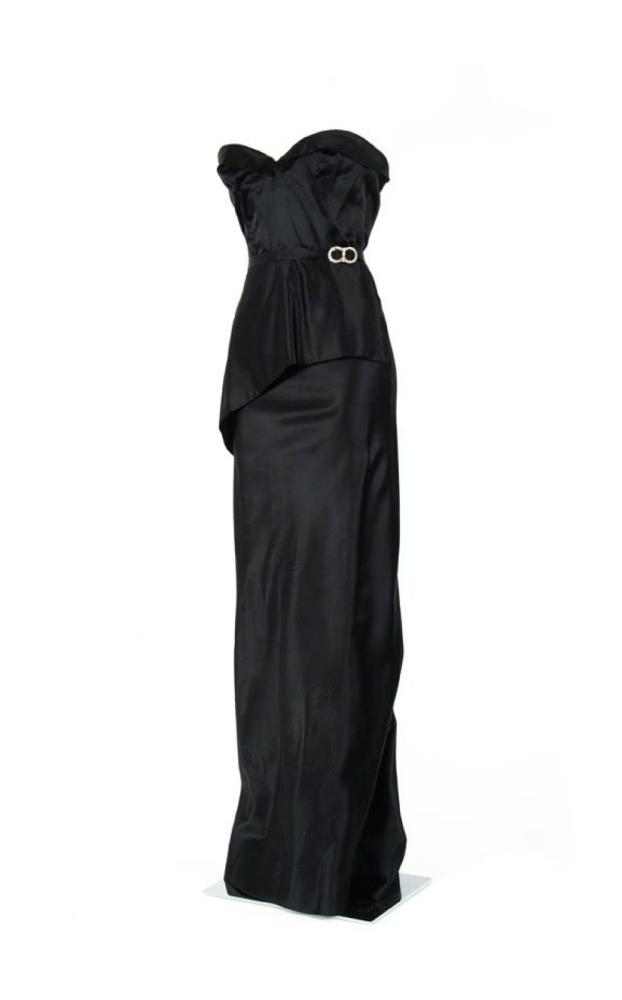 AZZARO

Robe du soir en satin noir, haut bustier à poitrine soulignée d’un revers, jupe fourreau fendue au dos et agrémentée d’une jupette à coupe asymétrique en biais avec fine ceinture ornée d’une boucle strassée. Griffe blache, graphime noir