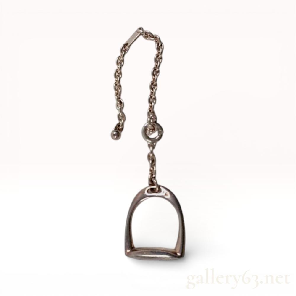 Description
Vintage Hermès charm crafted in sterling silver, formed as the houseâs iconic étrier (stirrup) motif. Suspended from a fine silver chain with a clasped attachment, allowing use as a bag charm or accessory accent. Polished silver finish with sculptural, equestrian-inspired form reflecting Hermèsâ heritage. 22.4 grams total.