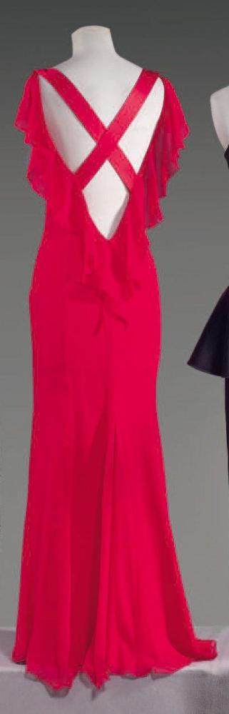 VALENTINO Roma, circa 2000

Robe longue en mousseline rouge, décolleté bateau sur dos nu souligné d’un volant de chaque côté, bretelles de satin se croisant sur ce dos, jupe fluide. Griffe blanche, graphisme or