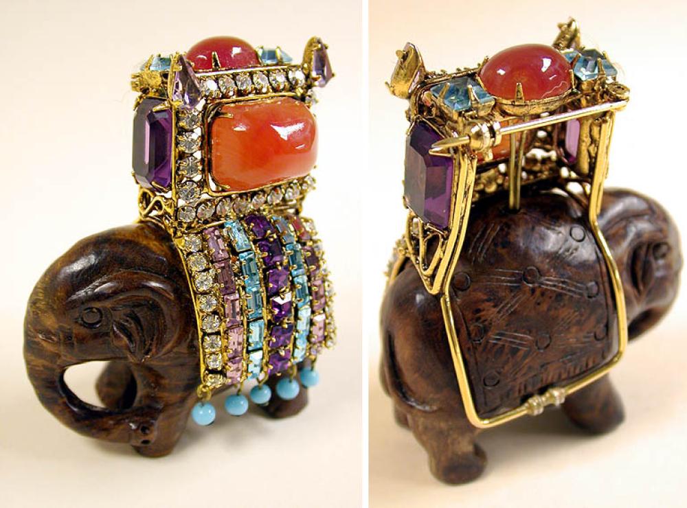 Iradj Moini Elephant Brooch

Lot 927
Iradj Moini Elephant Brooch
 The mahogany wood elephant carrying a gilt-metal howdah inset with coral colored stones, amethyst cabochons and turquoise, mauve and clear rhinestones, height 3 inches, marked: Iradj Moini.
Excellent condition.