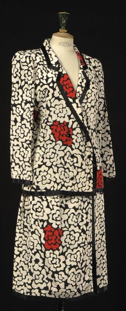 Emanuel UNGARO

Couture, N°5859, Printemps - Eté 1980 Tailleur en soie à motif floral blanc et rouge sur fond noir, veste à col tailleur gansé de soie unie noire, double boutonnage, manches longues, jupe porte-feuille. Griffe blanche, graphisme noir (auréoles)