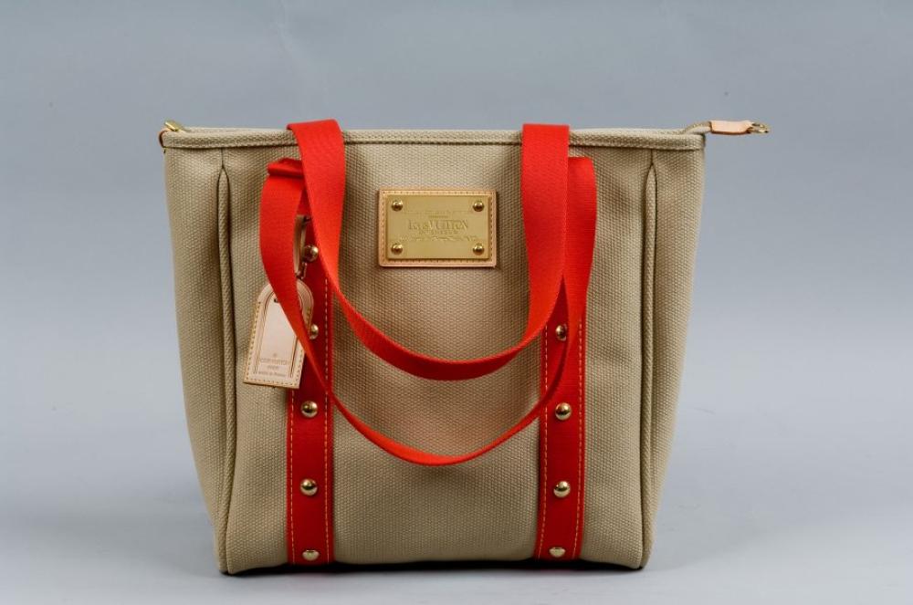 Louis VUITTON

Sac modèle "cabas" en toile antigua beige et sangles corail cloutée rehaussées de surpiqures jaune, fermeture éclair, double poignée, devant agrémenté d’une plaque en laiton doré montée sur cuir naturel et portant l’inscription "Louis VUITTON  inventeur 101, avenue des Champs Elysées, PARIS". Très bon état