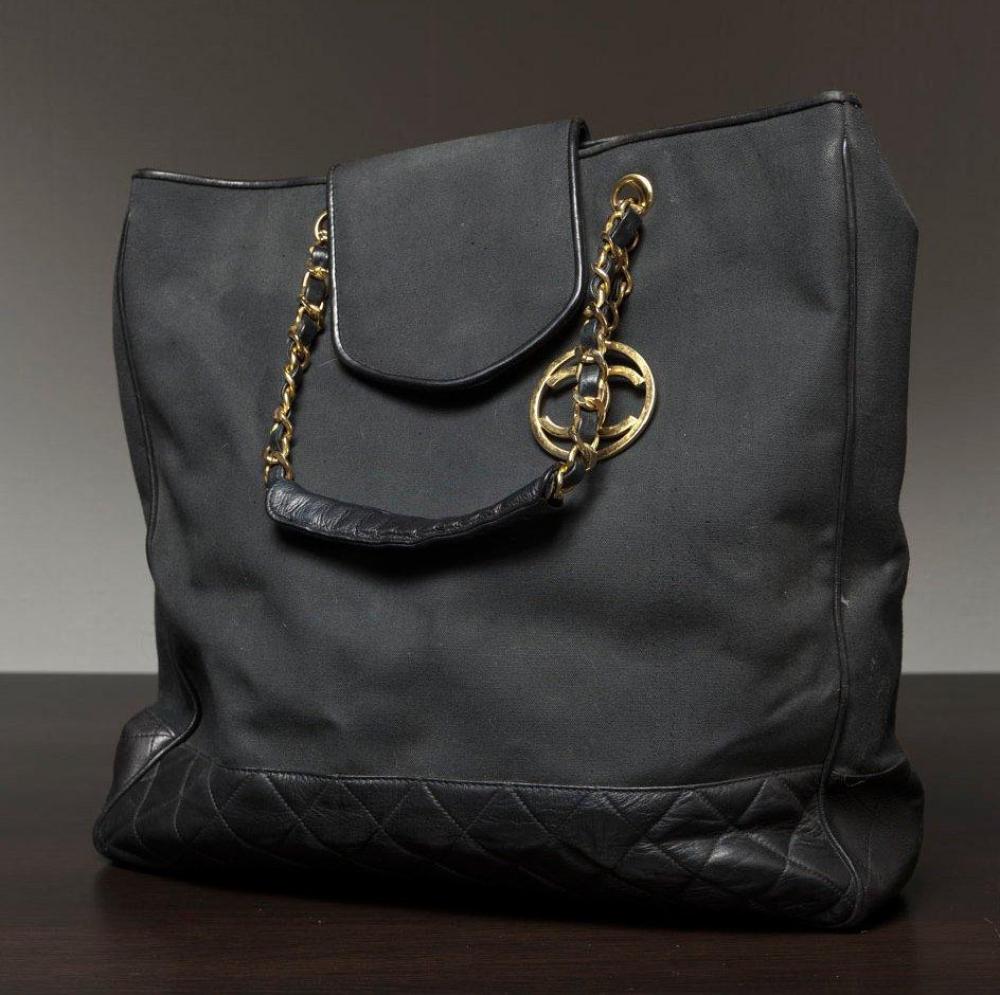 CHANEL

Sac cabas en toile noire, fond en cuir agneau matelassé à la couleur, fermeture sous patte pressionnée, double poignée en métal doré entrelacé de cuir. (taches). Long: 35 cm