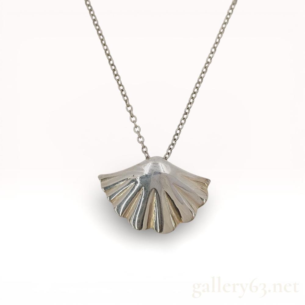 Description
Elsa Peretti for Tiffany and Co. sterling silver pendant necklace featuring a ginkgo leaf motif. The fan-shaped pendant is designed with polished radial fluting and a smooth convex top, suspended from a fine cable chain with a spring ring clasp. The reverse of the pendant is stamped with Tiffany and Co. and 925, while an oval tag near the clasp bears the Elsa Peretti script signature.
Pendant: 1 inch width
Chain: 16 inches length.