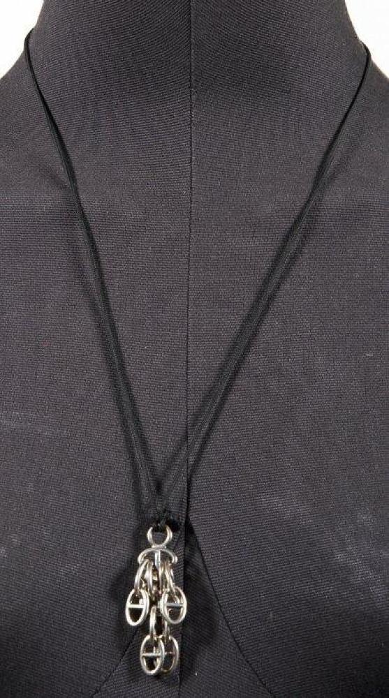 HERMES PARIS

Tour de cou en lien noir retenant un pendentif en argent agrémenté de charms figurant des maillons "Chaîne d’Ancre". Poids: 25,0 gr environ
