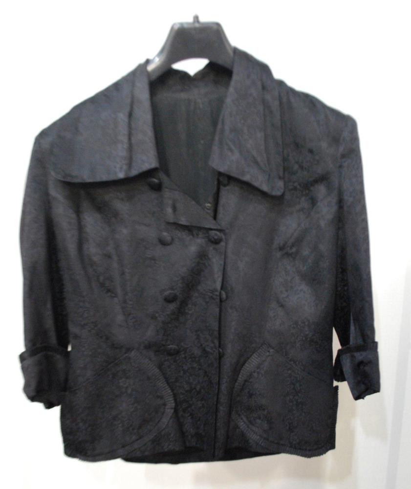 Anonyme

Veste en crêpe façonnée noire des années 40, col châle, double boutonnage, deux poches plaquées festonnées, manches 3/4 à revers également festonnée. Taches