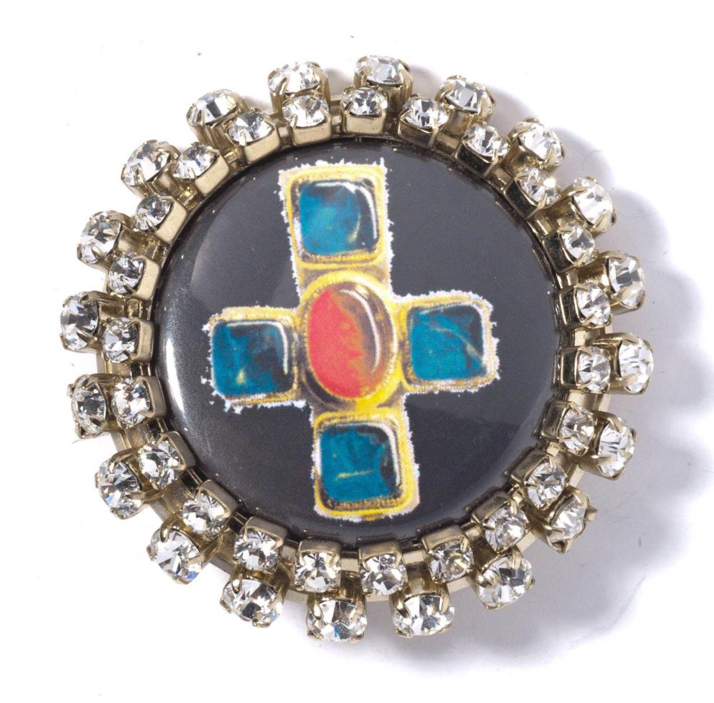 CHANEL

Broche de forme circulaire ornée au centre d’une croix sous plexiglass, entourage de strass. Signée
