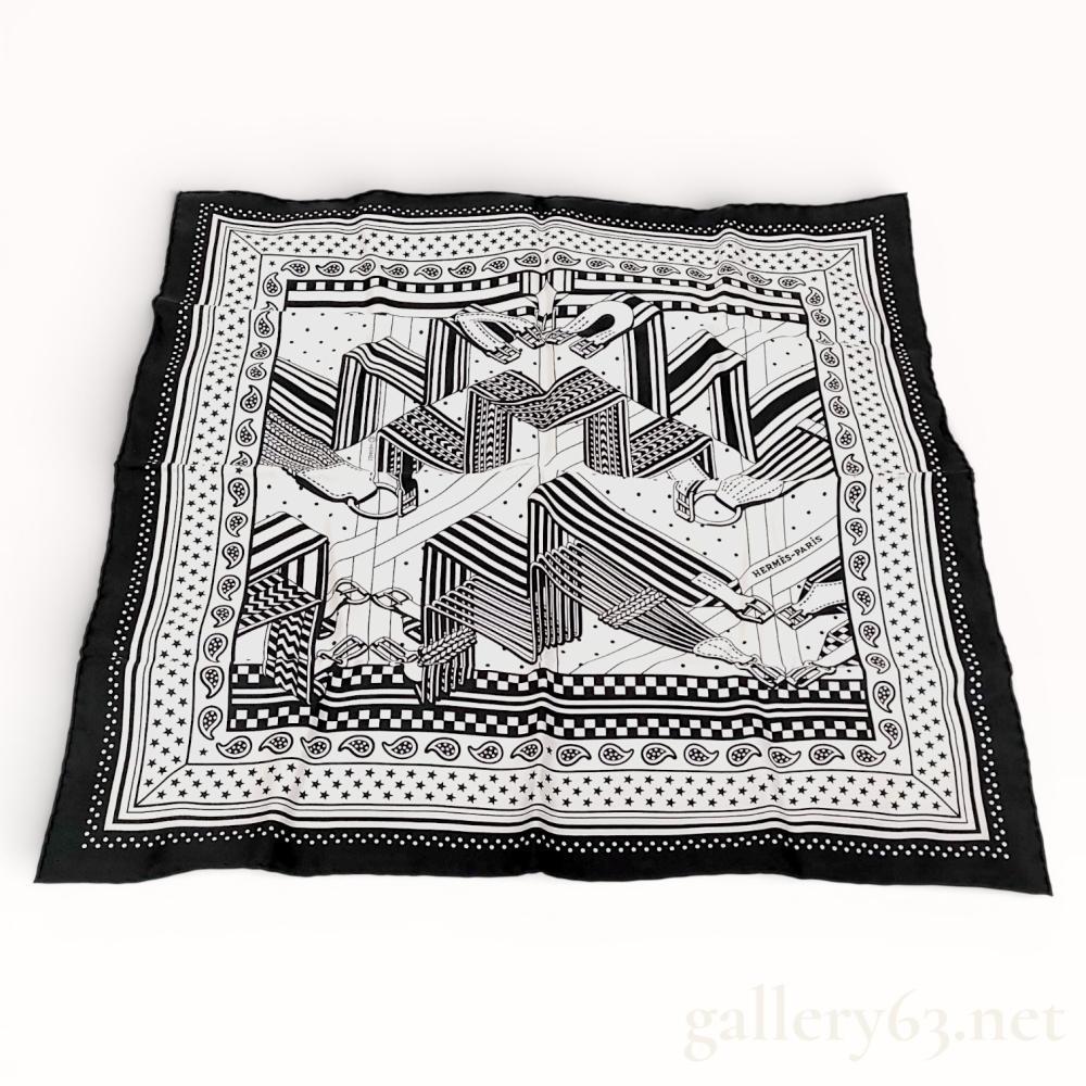 Description
Hermes silk bandana scarf in the Zigzag au Sangle pattern, contemporary. The 100 percent silk twill features a graphic black and white design of stylized equestrian straps and buckles accented by star, paisley, and checkerboard borders. Construction includes signature hand-rolled edges with a printed copyright mark and attached fabric care tag.
Dimensions: 55 cm x 55 cm (approximately 21.65 x 21.65 inches).