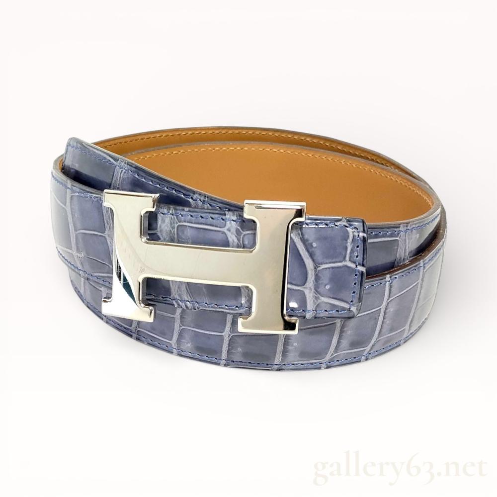 Description
Hermès belt crafted in blue crocodile leather with a smooth tan leather reverse. Strap fitted with a polished silver-tone Hermès H buckle in a classic rectangular form. Leather presenting a structured finish with stitched edges and consistent embossing throughout. Belt designed with a reversible construction and a clean, tailored profile consistent with Hermès accessories. Stamped Hermes Paris Made in France A [K] 80 C. 13