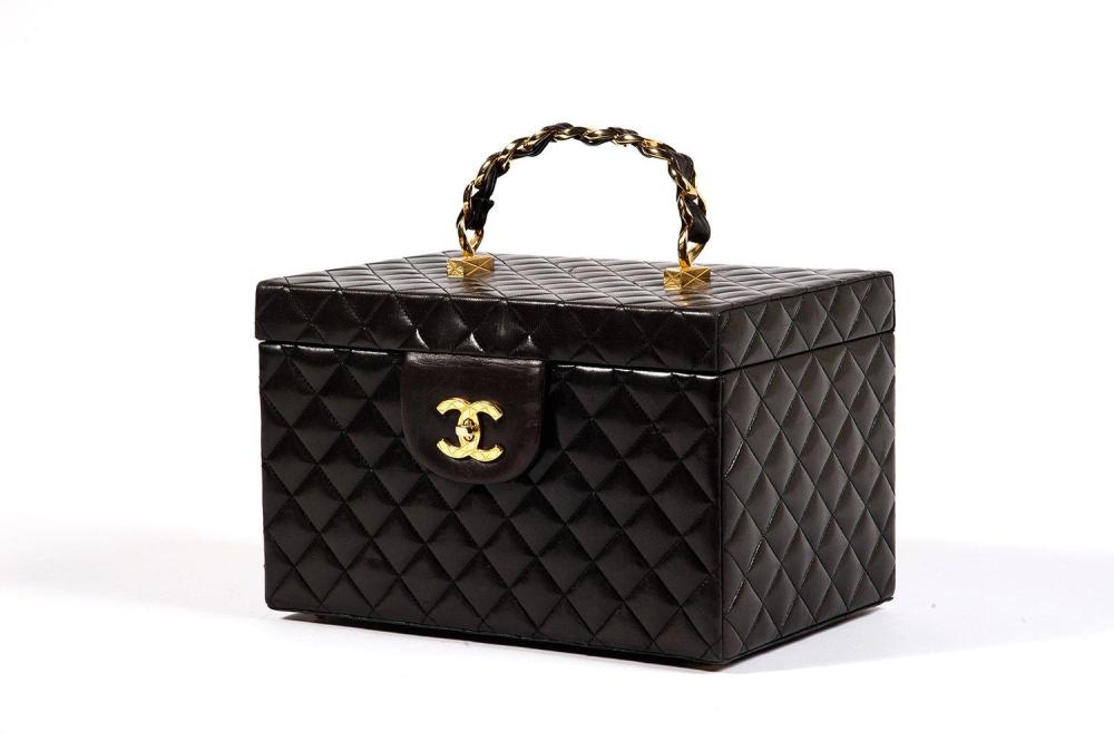 CHANEL

Vanity en cuir agneau matelassé noir, fermeture siglée en métal doré ciselé sur languette, attaches et poignée rigide en métal doré entrelacée de cuir, miroir intérieur. Bon état (légères égrenures). Dimensions: 31 x 20 x 19cm