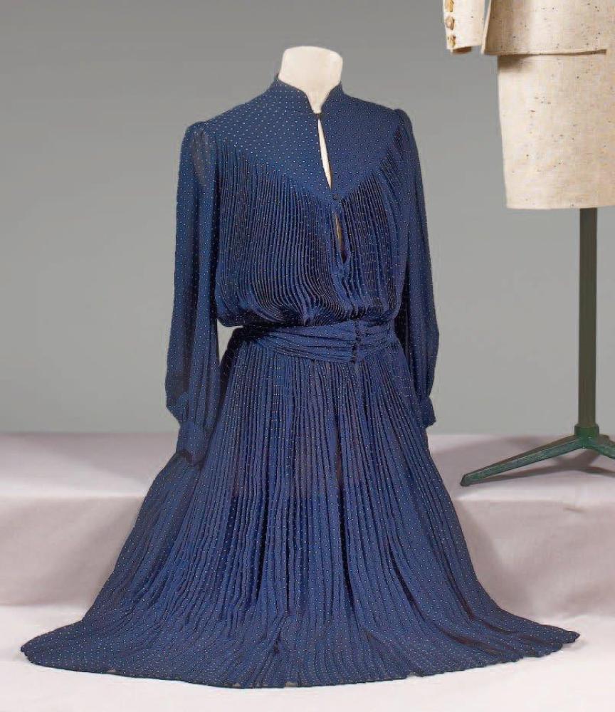 VALENTINO Boutique, circa 1978 / 1980

Robe en mosseline marine à petits pois blancs, buste et jupre ample plissé soleil, col droit sur profonde échancrure et empiècement, manches longues bouffantes, ceinture ruban soulignant la taille. Griffe blanche, graphisme noir