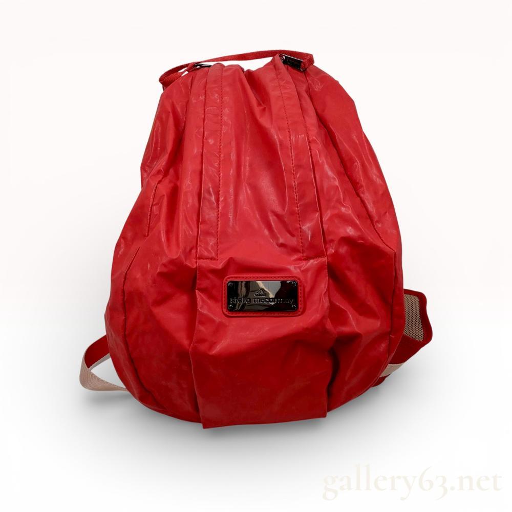 Description
A versatile, oversized sport backpack from the Adidas by Stella McCartney collaboration. The bag features a vibrant red coated synthetic exterior with a characteristic crinkled texture. Designed for high-performance use, it includes a breathable beige mesh back panel, padded adjustable shoulder straps with reflective detailing, an adjustable chest strap, and a waist belt for secure carrying. The interior is lined in gray textile and contains multiple storage compartments. The front is adorned with a prominent black-tone metal "adidas | stella mccartney" branding plaque. Approximately 19 x 14 x 6 inches.