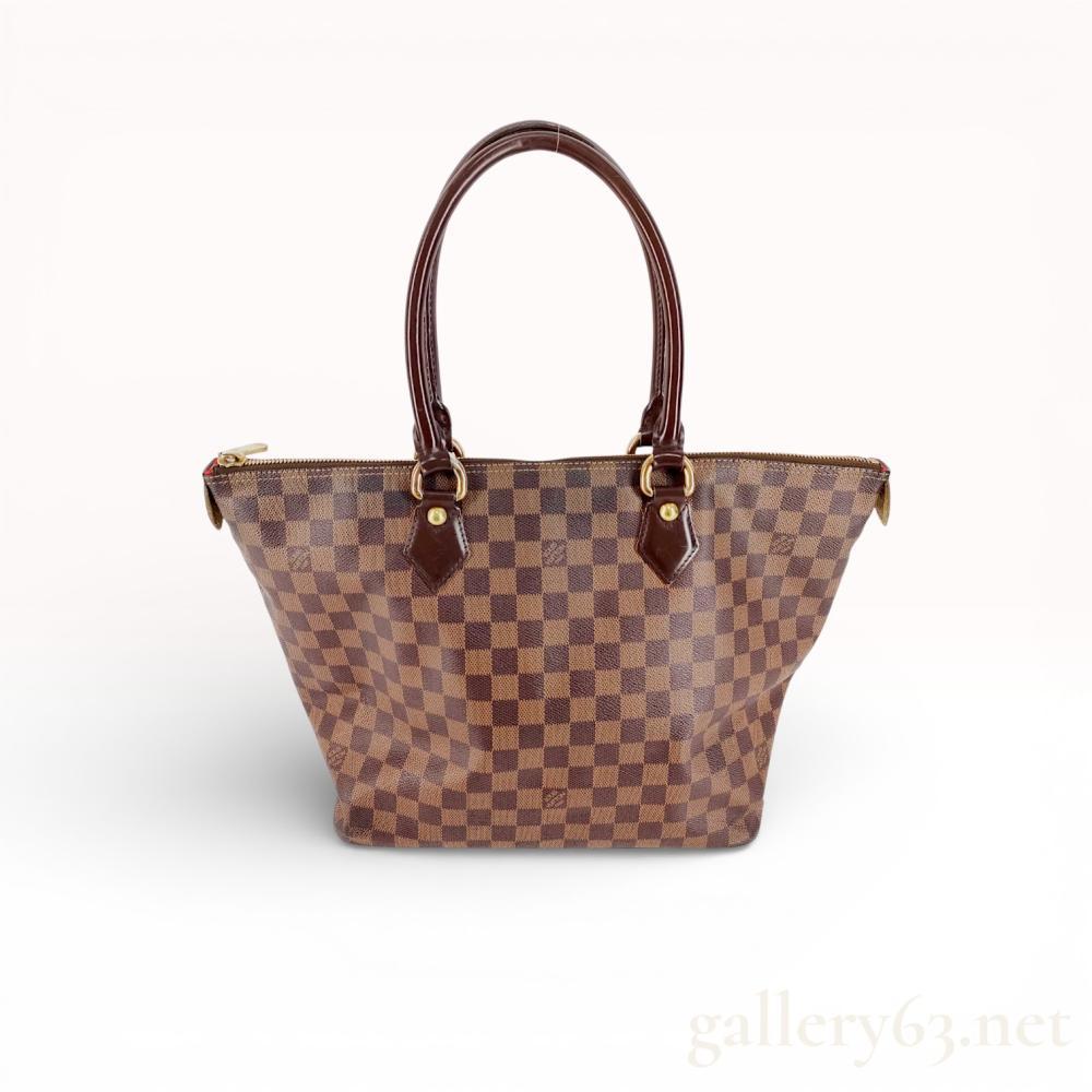 Description
Louis Vuitton Saleya MM tote bag in Damier Ebene coated canvas with dark brown leather trim and gold-tone brass hardware. The exterior features rolled leather handles and a top zipper closure, while the interior is lined in red alcantara with two slip pockets and a D-ring. Branding is present on the canvas pattern, hardware rivets, zipper pull, and a heat-stamped leather side tab.
11 inches H x 17 inches W x 7 inches D; Handle drop: 8 inches.