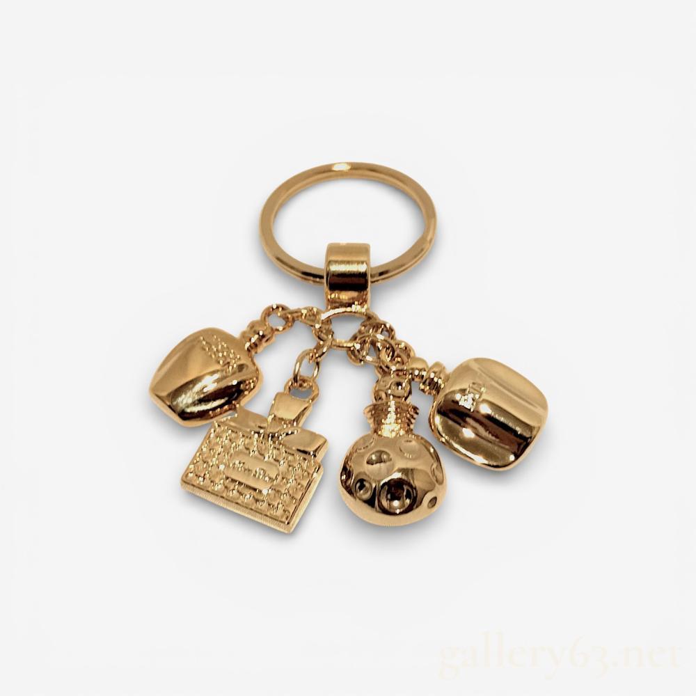 Description
Christian Dior gold-tone metal bag charm and keyring featuring four miniature perfume bottle charms. The charms are modeled after the house’s iconic fragrances, including Dolce Vita, Tendre Poison, and Dune, suspended from a central split-ring by individual link chains. The reverse of the charms bear embossed fragrance names, and the item is accompanied by a white Christian Dior Paris presentation box.
Overall length: Approximately 2.25 inches
Charm cluster width: Approximately 2.4 inches.