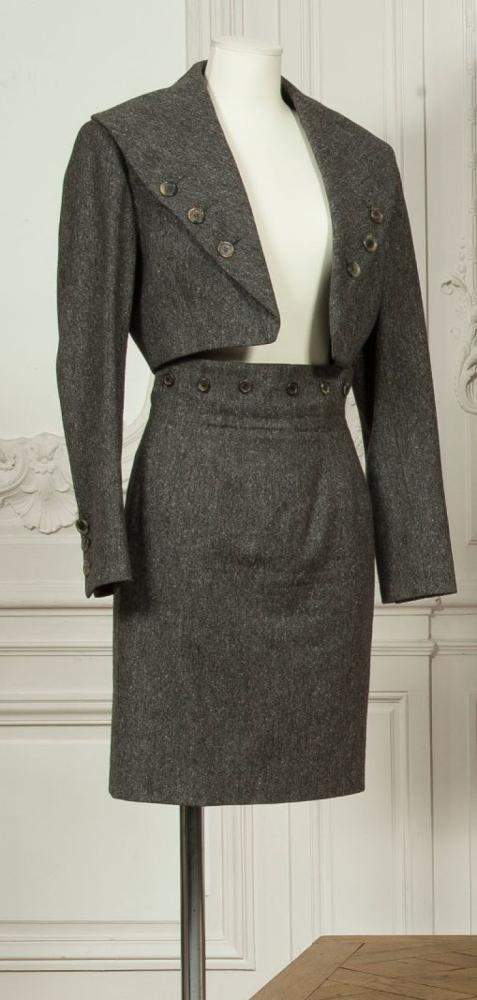 CHLOE par Karl Lagerfeld

Tailleur en tweed gris chiné, spencer à col châle boutonné, manches longues, jupe droite, fente dos. Griffe blanche, graphisme noir